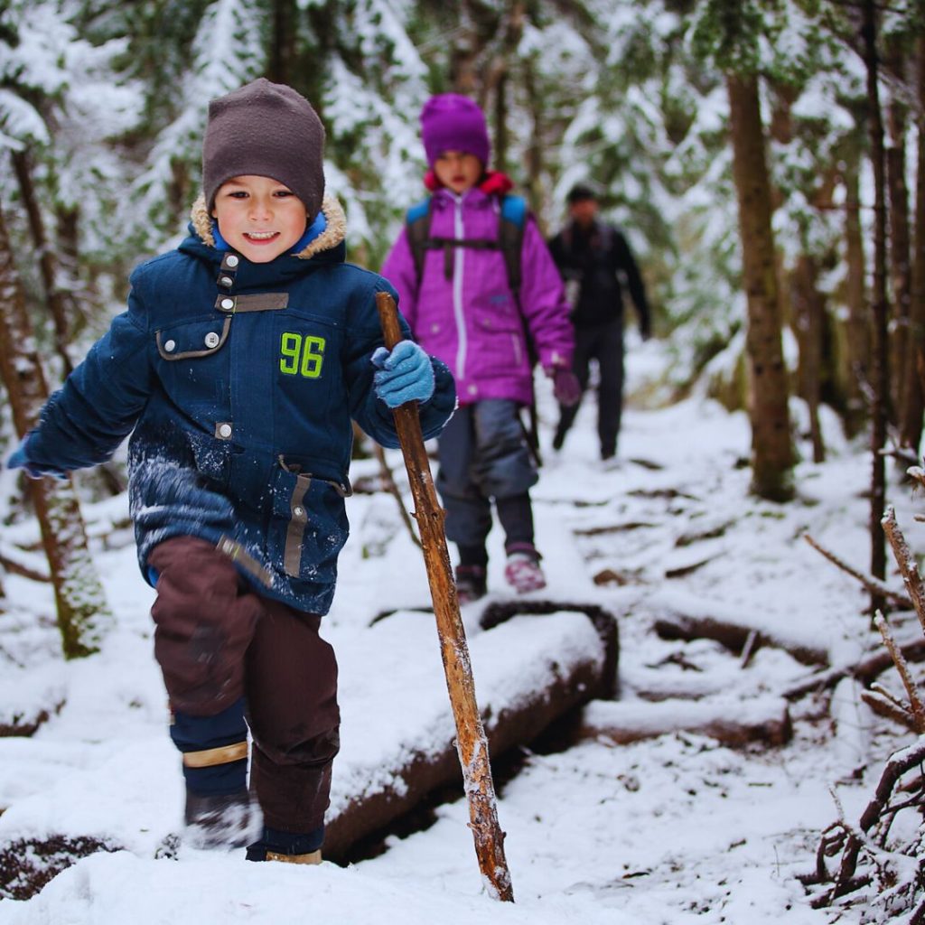 children hiking through a snowy woods